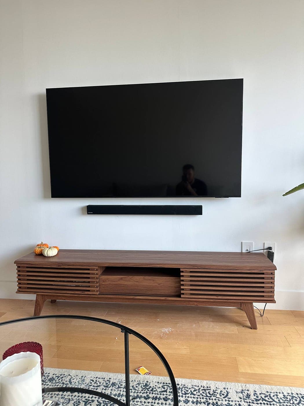 Large TV mounted with concealed cords above a walnut console in NYC